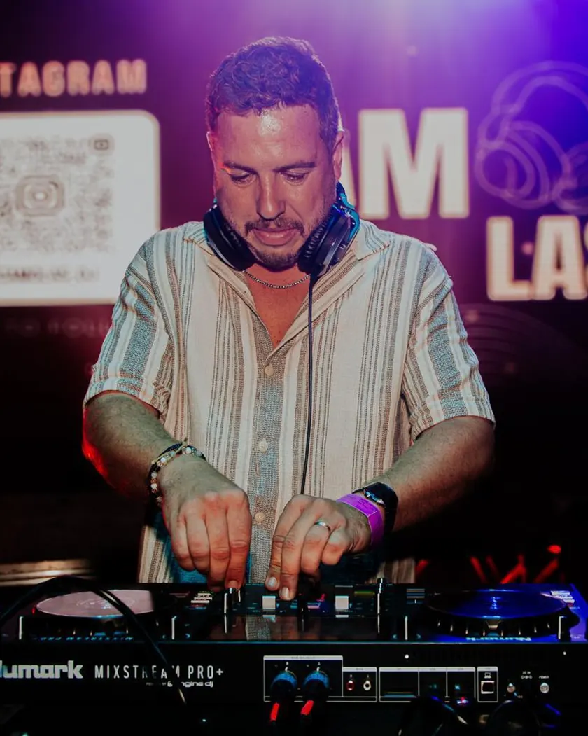 Camolas DJ na cabine, com auscultadores, em frente ao logótipo Camolas